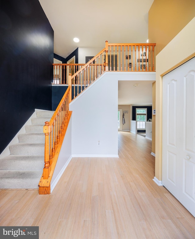 stairs featuring hardwood / wood-style flooring and a towering ceiling