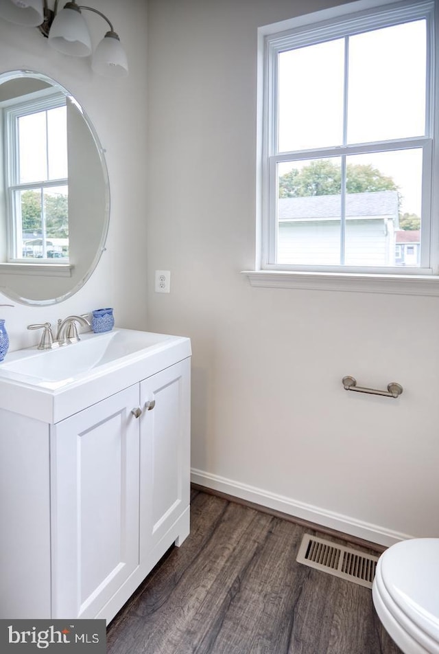 bathroom with hardwood / wood-style flooring, plenty of natural light, toilet, and vanity