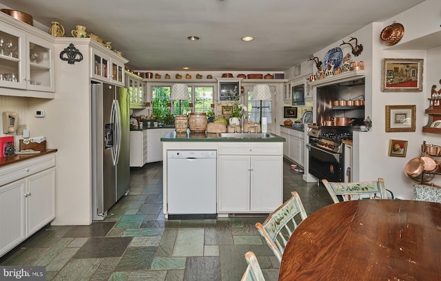 kitchen with stainless steel appliances, a center island, white cabinets, and sink