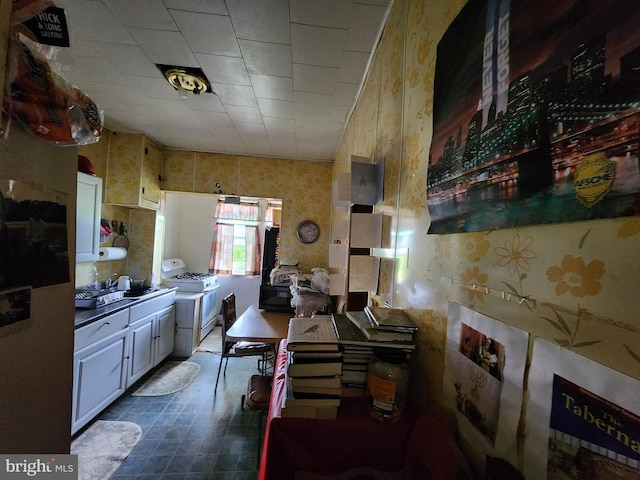 kitchen with white cabinets, white gas stove, and sink