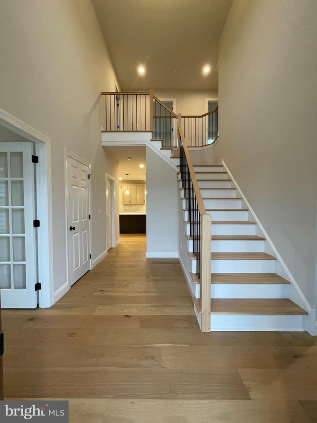 stairs featuring a high ceiling and wood-type flooring