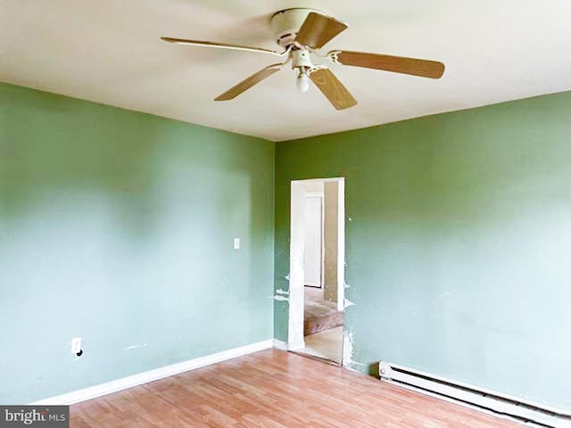 empty room with hardwood / wood-style flooring, baseboard heating, and ceiling fan