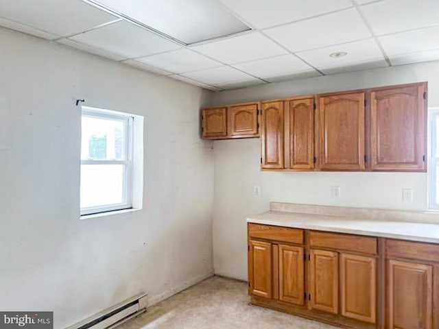 kitchen featuring baseboard heating, a paneled ceiling, and light colored carpet