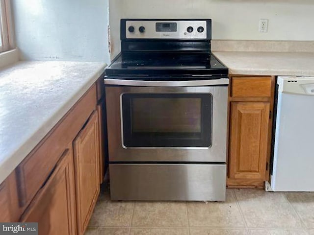 kitchen with stainless steel electric stove, light tile patterned floors, and white dishwasher