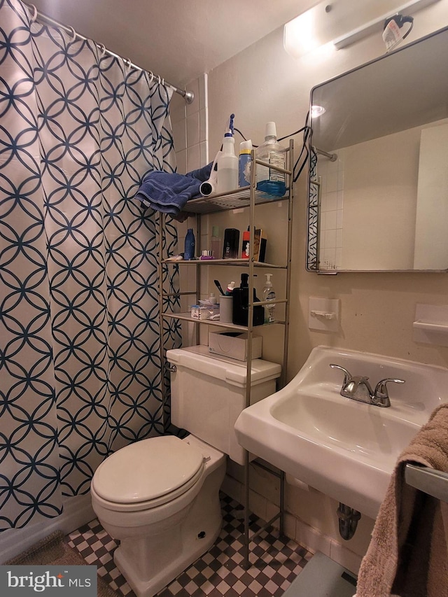 bathroom featuring tile patterned floors, curtained shower, and toilet