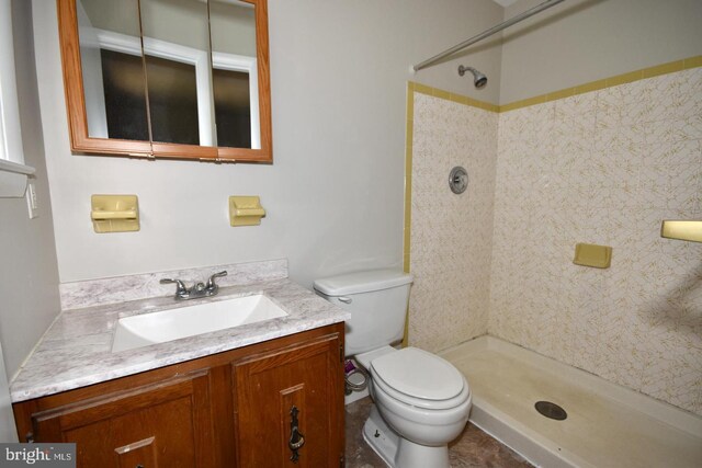 bathroom with a tile shower, tile patterned flooring, vanity, and toilet