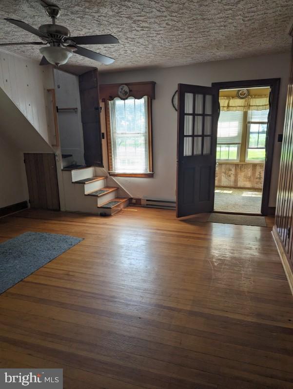 interior space with ceiling fan, hardwood / wood-style floors, and a baseboard heating unit