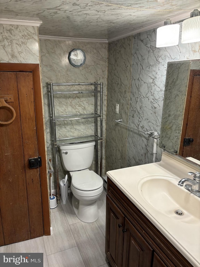 bathroom featuring toilet, vanity, and ornamental molding