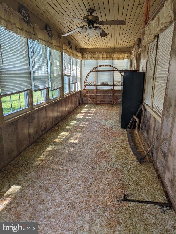 unfurnished sunroom featuring ceiling fan and wooden ceiling