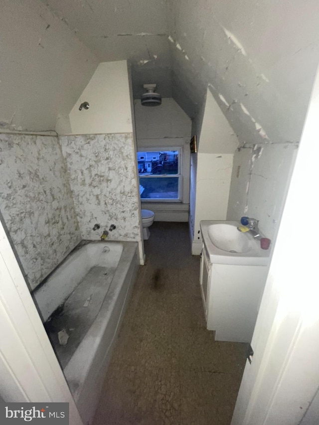 bathroom with a washtub, vanity, toilet, and lofted ceiling