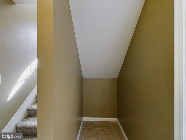 staircase featuring tile patterned floors and vaulted ceiling