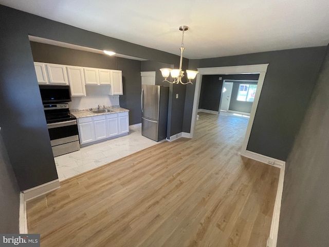 kitchen with appliances with stainless steel finishes, light wood-type flooring, white cabinetry, and sink