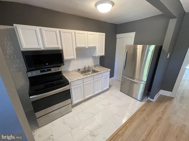 kitchen with white cabinetry, sink, stainless steel appliances, and light hardwood / wood-style floors