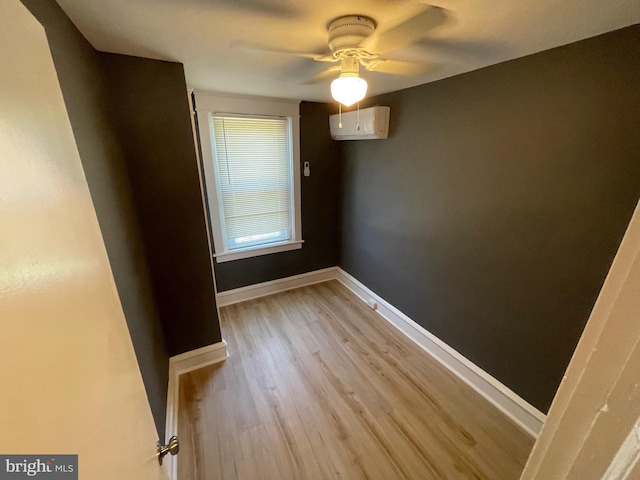 empty room with a wall mounted air conditioner, light hardwood / wood-style floors, and ceiling fan