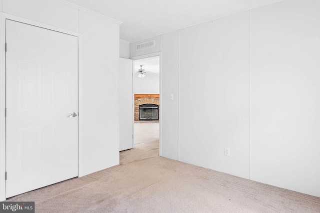 spare room with light carpet, a fireplace, and ceiling fan