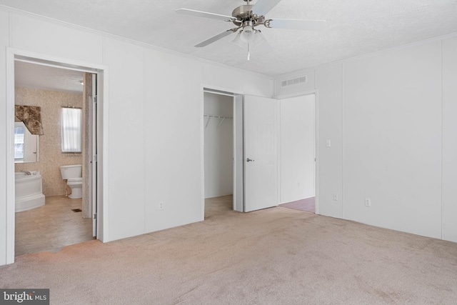 unfurnished bedroom with connected bathroom, ceiling fan, a closet, and light colored carpet