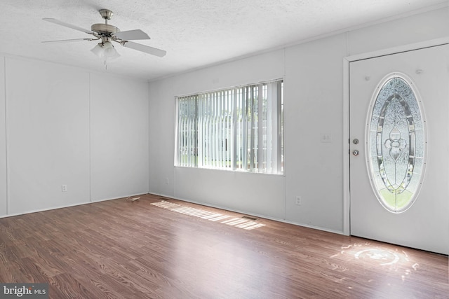 foyer entrance with ceiling fan, wood-type flooring, and a textured ceiling