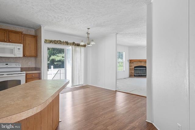 kitchen featuring an inviting chandelier, a stone fireplace, light hardwood / wood-style floors, decorative light fixtures, and range