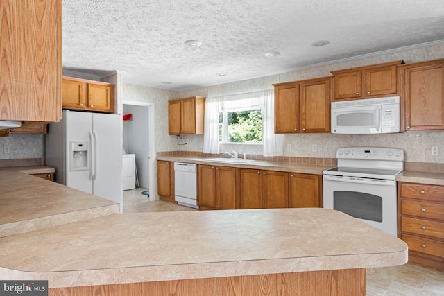 kitchen featuring a textured ceiling, washer / dryer, white appliances, and sink