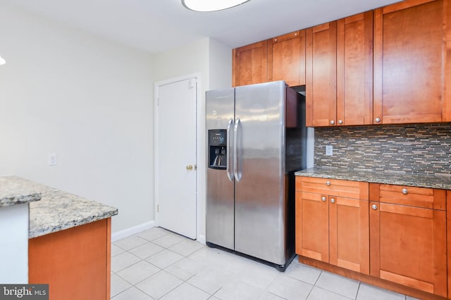 kitchen featuring stainless steel fridge, light stone countertops, decorative backsplash, and light tile patterned floors