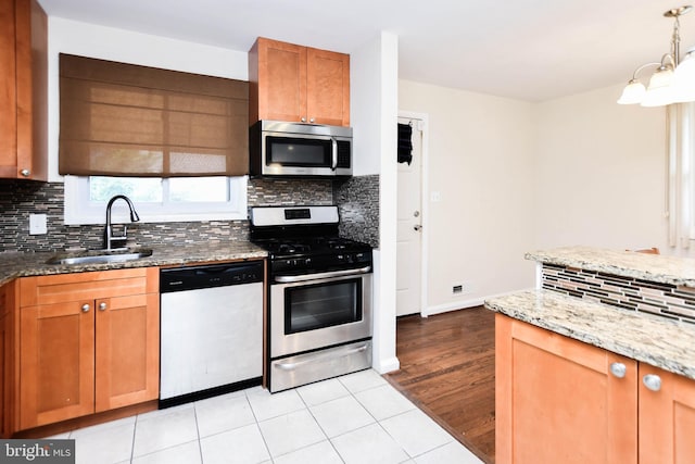 kitchen featuring sink, stainless steel appliances, light stone counters, tasteful backsplash, and light tile patterned flooring