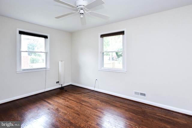 spare room featuring ceiling fan, dark hardwood / wood-style floors, and a healthy amount of sunlight