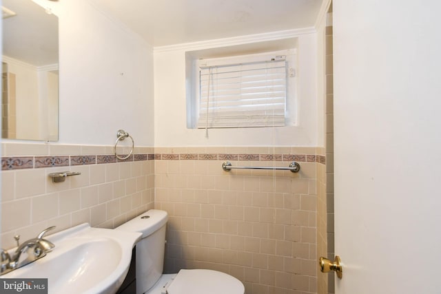 bathroom featuring ornamental molding, toilet, sink, and tile walls