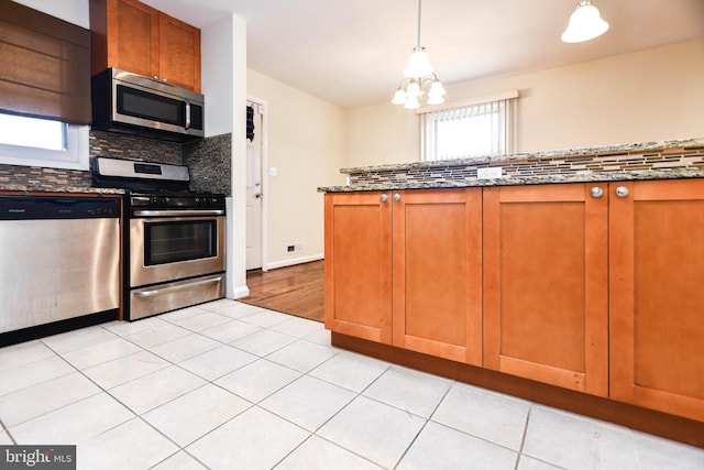 kitchen with pendant lighting, light tile patterned floors, stainless steel appliances, and stone counters