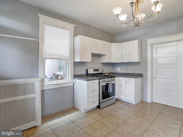 kitchen with white cabinets, light tile patterned floors, an inviting chandelier, and stainless steel gas range oven