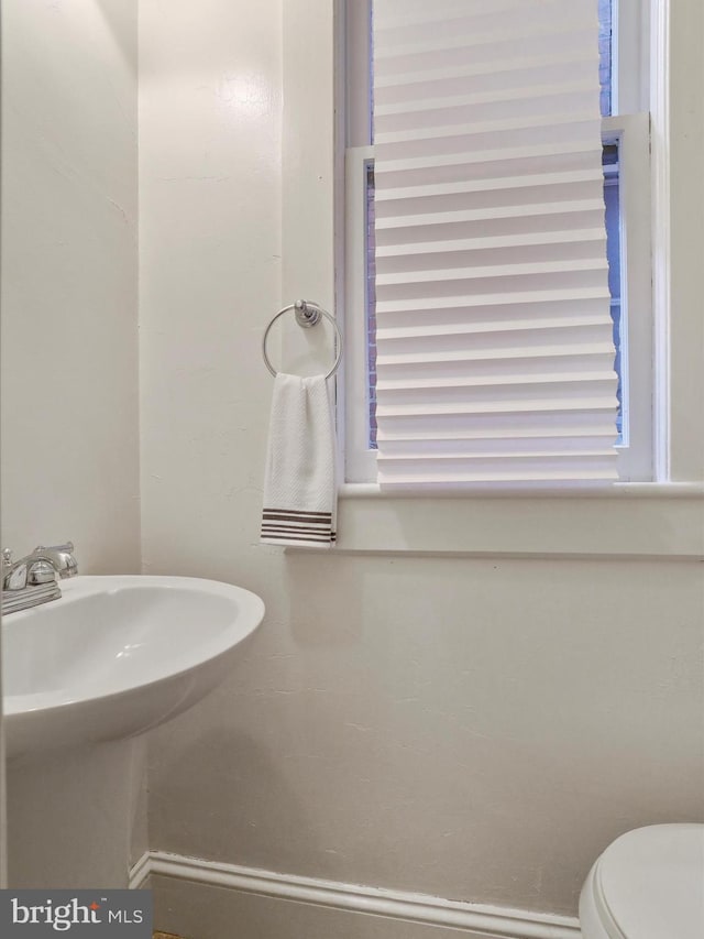 bathroom with toilet, a healthy amount of sunlight, and sink