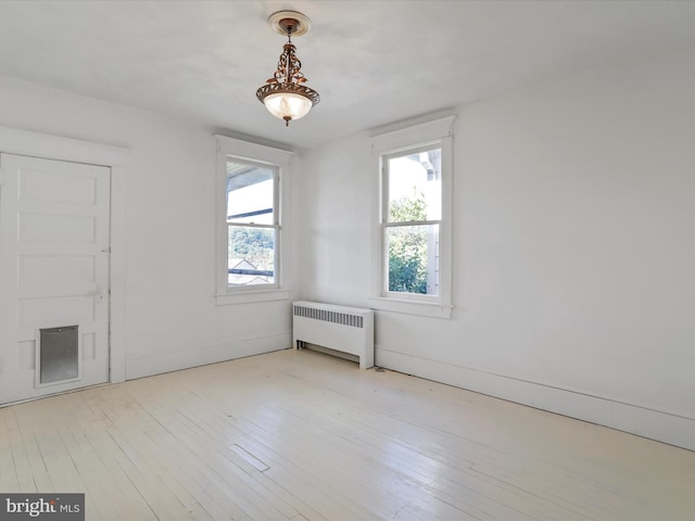 unfurnished room with light wood-type flooring and radiator heating unit