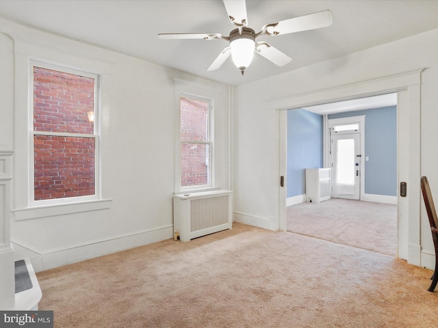 empty room featuring light carpet, radiator, and ceiling fan