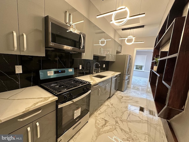 kitchen with decorative backsplash, light stone counters, stainless steel appliances, sink, and hanging light fixtures