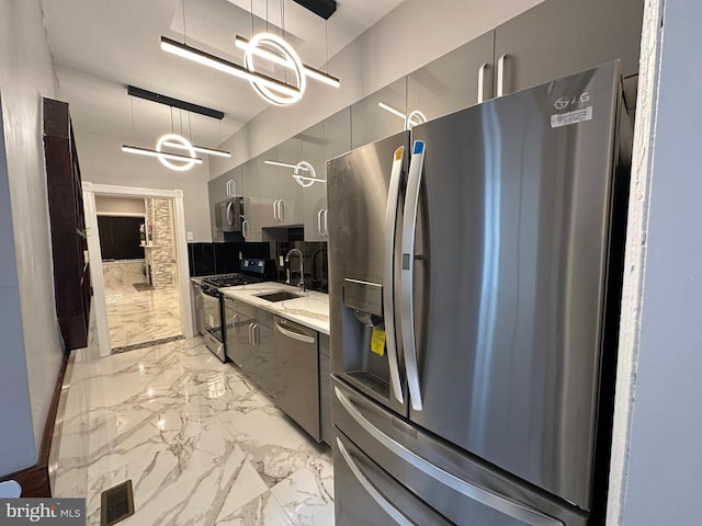 kitchen with light stone counters, stainless steel appliances, sink, decorative light fixtures, and a notable chandelier