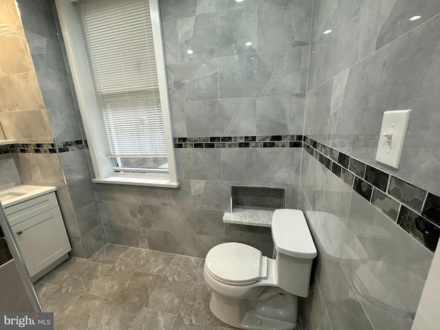 bathroom featuring vanity, tile walls, and toilet