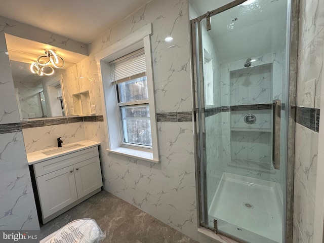 bathroom with vanity, a shower with shower door, and tile walls