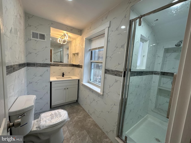 bathroom featuring vanity, toilet, a shower with door, and tile walls