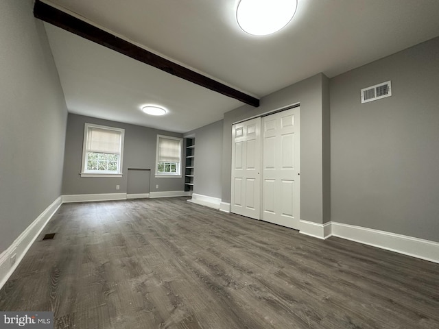 interior space with beam ceiling, a closet, and dark wood-type flooring