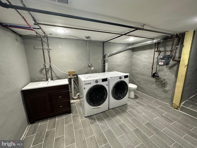 washroom with hardwood / wood-style flooring, separate washer and dryer, and sink