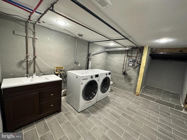 clothes washing area featuring washer and dryer, light hardwood / wood-style floors, and sink