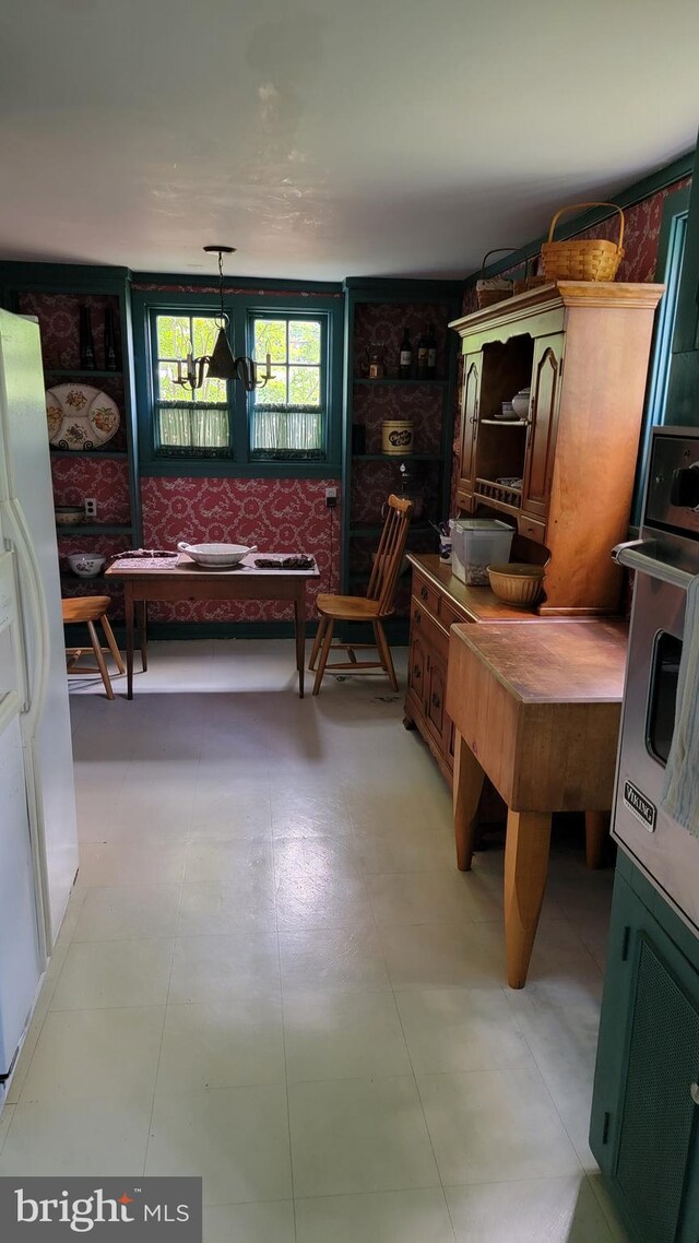 kitchen with hanging light fixtures, white fridge, and light tile patterned floors