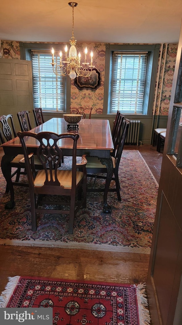 dining space with radiator heating unit, a chandelier, and hardwood / wood-style flooring