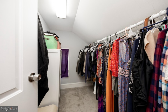 walk in closet with lofted ceiling and light colored carpet