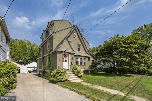 view of front of home featuring a garage, an outbuilding, and a front lawn