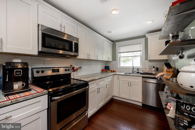 kitchen featuring white cabinets, decorative backsplash, light stone countertops, appliances with stainless steel finishes, and dark hardwood / wood-style flooring