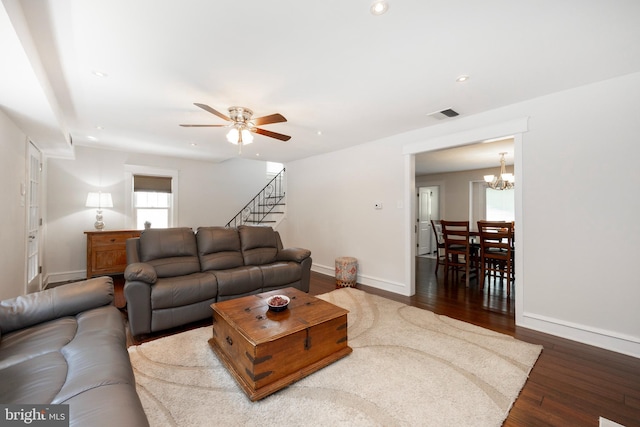 living room featuring dark hardwood / wood-style flooring and ceiling fan with notable chandelier