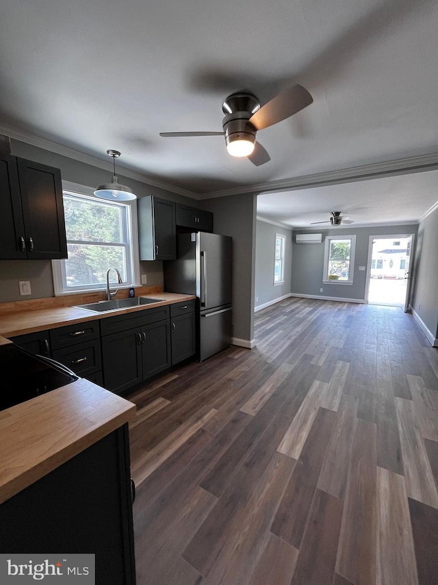 kitchen featuring decorative light fixtures, ceiling fan, sink, crown molding, and stainless steel fridge