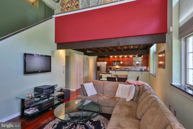 living room with beamed ceiling, hardwood / wood-style floors, and a high ceiling