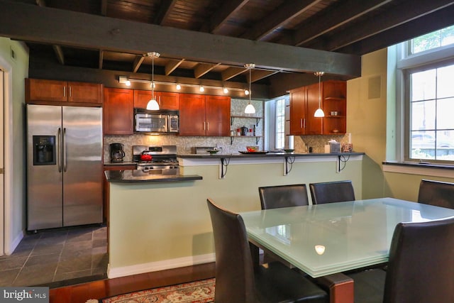 kitchen with pendant lighting, a breakfast bar, decorative backsplash, appliances with stainless steel finishes, and beam ceiling