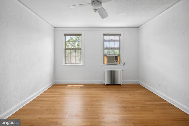 spare room with cooling unit, light wood-type flooring, and radiator heating unit